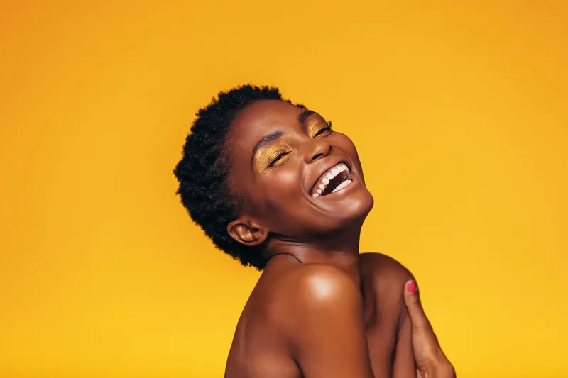A woman laughing against a yellow background